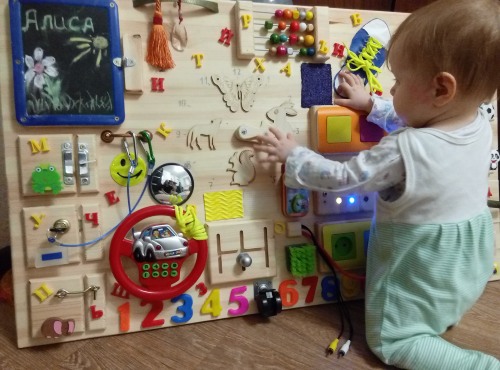 DIY-Entwicklungsboards für Kinder. So stellen Sie ein Busy Board her und befestigen Klettverschlüsse und Knöpfe. Foto