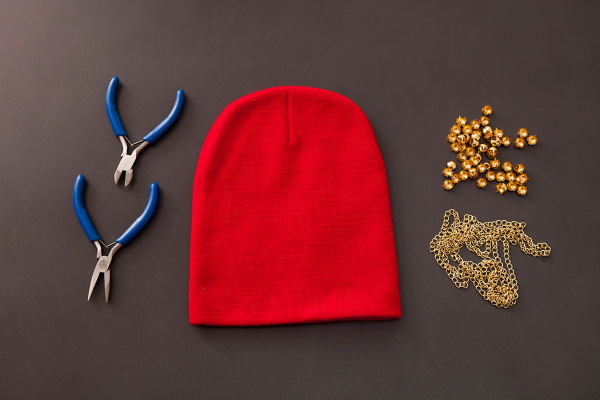 So verzieren Sie eine Strickmütze für Damen mit Perlen, Pelz, Strasssteinen und Rocailles. Foto