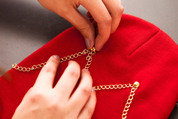 So verzieren Sie eine Strickmütze für Damen mit Perlen, Pelz, Strasssteinen und Rocailles. Foto