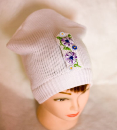 So verzieren Sie eine Strickmütze für Damen mit Perlen, Pelz, Strasssteinen und Rocailles. Foto