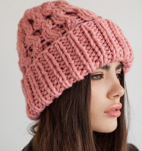 Eine große Strickmütze aus dicken Fäden mit Stricknadeln. Schema