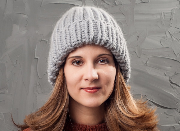 Eine große Strickmütze aus dicken Fäden mit Stricknadeln. Schema