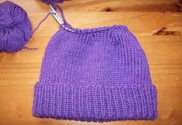 Mit Stricknadeln Maschen an einer Mütze abnehmen. Muster mit glatt rechts, 2x2, 1x1 Gummiband